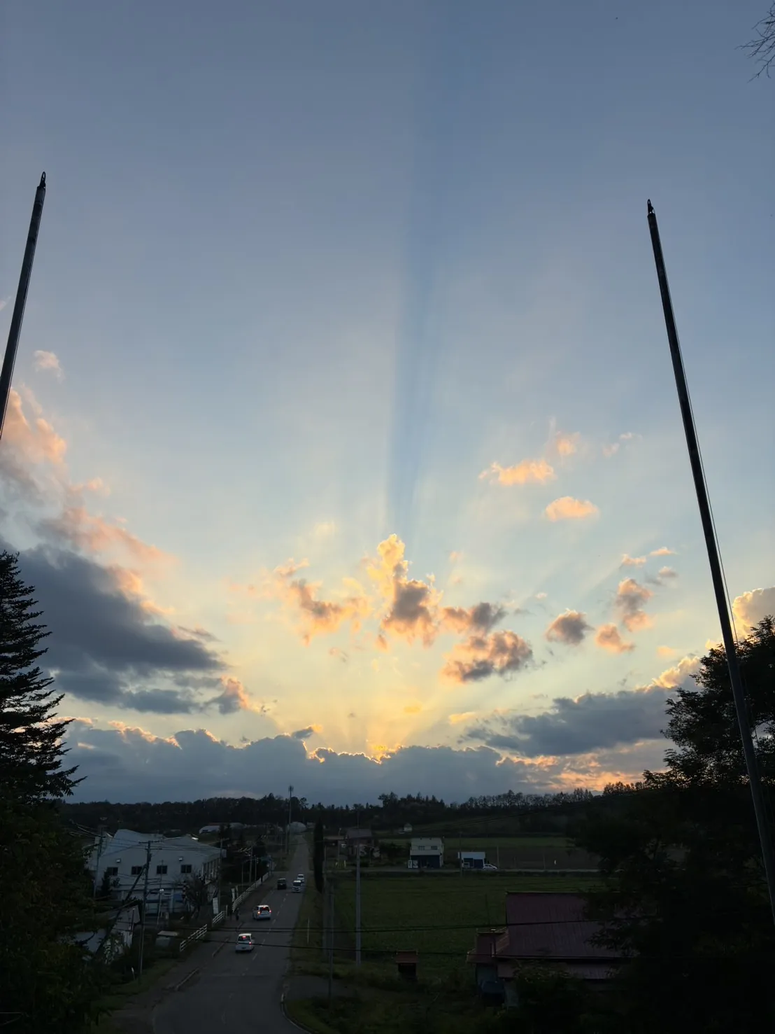 高台から見る、まちの上に広がる夕日の光芒